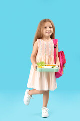 Poster - Happy little girl with backpack and lunchbox on blue background