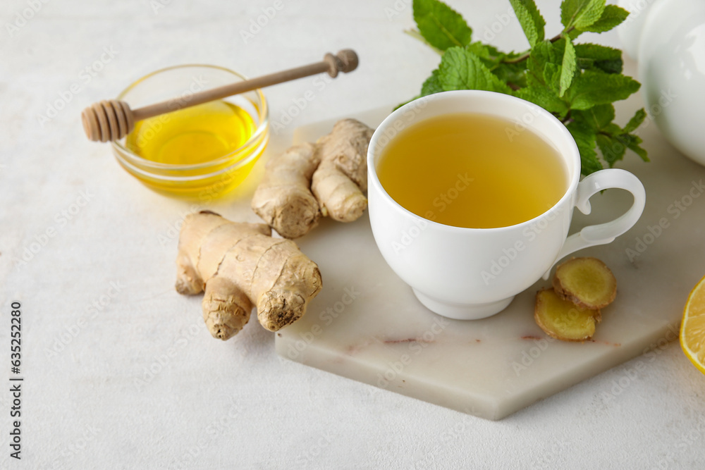Cup of ginger tea and bowl with honey on white background