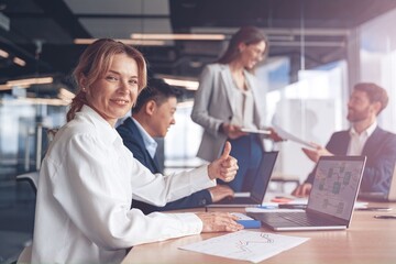 Wall Mural - businesswoman sitting at the office table with group of colleagues, working on laptop.