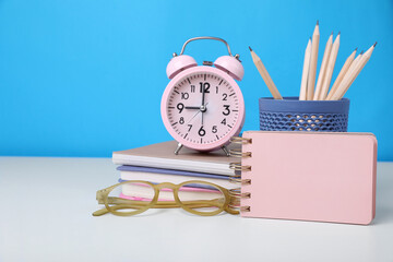 Sticker - Different school stationery, alarm clock and glasses on white table against light blue background, space for text. Back to school