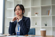 © bongkarn - A professional and determined Asian businesswoman sits at her desk.