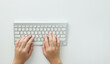 © sutlafk - Flat lay woman hands on white desk use pc computer silver keyboard. Top view. Female hands typing on keyboard at white table workplace. Home office workspace with keyboard mouse glasses.