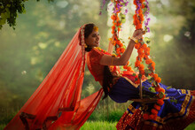 Young woman dressed up as Radha and sitting on a swing on the occasion of Janmashtami