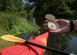 kompas trzymany w dłoni nad rzeką, w przerwie przeprawy kajakowej w słoneczny dzień