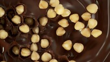 Super Slow Motion Shot Of Peeled Hazelnuts Falling Into Swirling Melted Chocolate At 1000 Fps.