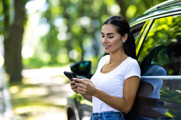 Wall Mural - Young woman smile and use mobile phone touching the screen inside the car