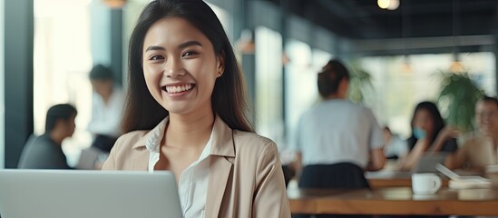 Poster - Smiling Asian woman in work attire uses laptop at office researching happily radiating positive energy executing business plan