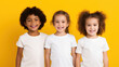 Little girls stand together, wearing white t-shirts, diverse preschool children smiling, yellow background, photo of apparel mock-up