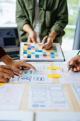  UX developer and ui designer brainstorming about mobile app interface wireframe design with customer breif and color code at office..
