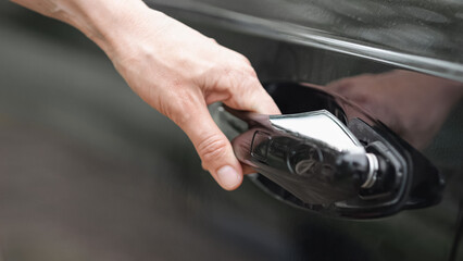 Automobile owner pressing small button to open modern car on road. Female driver struggles to open car jerking at vehicle doorknob closeup