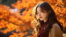 紅葉と女性、オレンジ色の秋の木を背景にした日本人女性