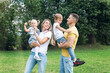 © Анна Демидова - Happy family with children in the park on a sunny day. Mom, dad and little daughter and son in jeans and white t-shirts laugh and hug. Love and tenderness.