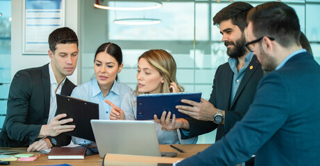 Wall Mural - Group of diverse business people discussing and reviewing paperwork, planning tasks and company goals at conference table during business meeting in the office.