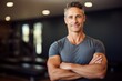Portrait of handsome man standing with arms crossed in fitness studio looking at camera