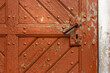 Close-up of an old, church wooden door with a handle and keyhole. The door is made from planks of wood that have been weathered by the elements over time, giving it a rustic look.