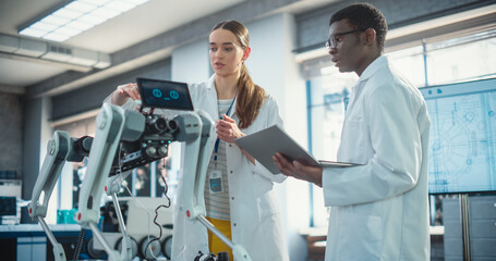 Poster - Two Multiethnic Industrial Robotics Specialists Working on a Mobile Robot, Using Laptop. Black Male Young Engineer In Lab Coat Discussing an Automated AI Robotic Dog with his Female Project Supervisor