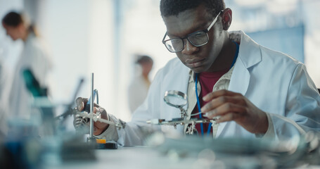 Aufkleber - Portrait of Black Male Lab Specialist Carefully Soldering a Circuit Board in a Manufacturing Industrial Company. Professional Man in Lab Coat Working on the Latest Technological Project For a Startup