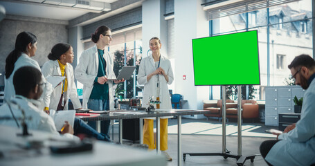 Fototapete - Group of Students Listening to Their Robotics Female Professor Who Uses Green Screen Monitor in a Laboratory. Team of Engineers Having Meeting and Discussing Manufacturing Ideas, Using High Technology