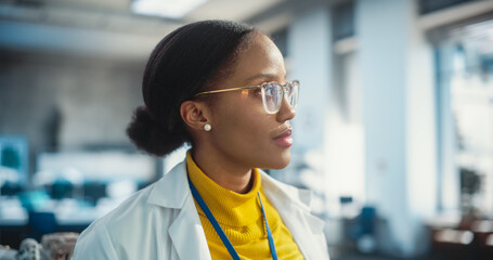 Poster - Portrait of Young Dreamy Black Woman Wearing Glasses and a Lab Coat, Looking Out Of Window. Future Engineer Building Scientific Career. Industrial Manufacturing Student in University Laboratory.