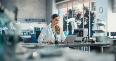 Portrait of Professional Female Scientist Working in Industrial Lab Using Laptop Computer. Successful Project Manager Making Strategy Plans for Industrial Production Company, Using Technology