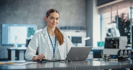 Aufkleber - Portrait of Caucasian Young Female Scientist Using Laptop Computer, Looking at Camera and Smiling in a Laboratory. Confident Professional Woman Working as Lead Engineer, Monitoring Technology Projects