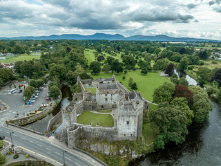 Wall Mural - Aerial view of Cahir castle and town in Ireland with Tower House, outer castle, circular, rectangular towers, banquette hall, guarding the crossing on the River Suir with a waterfall and golf course