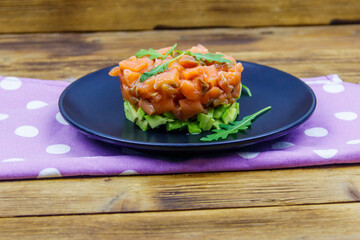 Wall Mural - Salmon tartare with avocado and arugula on wooden table