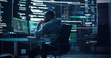 Leinwandbilder - Portrait of a Black Man Working on Computer, Typing Lines of Code that Appear on Big Screens Surrounding him in Monitoring Room. Male Programmer Creating Innovative Software Using AI Data and System
