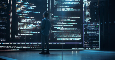 Leinwandbilder - Portrait of Young Woman Working on Laptop Computer, Looking at Big Digital Screen Displaying Back-end Code Lines. Professional Programmer Developing a Big Data Interface Software Project