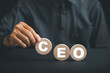 © sorapop - Businessmans hand picks up wooden circle with CEO text, symbolizing CEO. HR officer searches for leader and CEO. HR manager selects employee. Leader stands out from crowd. HR, HRM, HRD concepts.