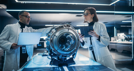 Fototapete - Professional Multicultural Team of Female and Male Engineers Working On Industrial Jet Turbine in Factory Development Workshop. Tech Facility with Machines, Computers and Advanced Research Equipment