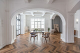 a chic expensive bright interior of a huge living room in a historic mansion with arched arches, columns and white walls decorated with ornaments and stucco.