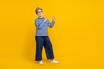 Full length photo of cheerful pensioner wear trendy jeans clothes two arm presenting offer empty space isolated on yellow color background