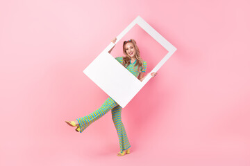 Full body photo of pretty young girl hold photo polaroid frame dance dressed stylish green print outfit isolated on pink color background