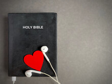 Earphones With Red Heart On The Bible. Symbolises Devotion And Love For Hearing God's Words. Christianity Concept.