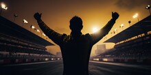 Silhouette Of A Racing Driver Celebrating Victory In A Race Against The Backdrop Of The Bright Lights Of The Stadium.