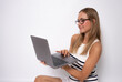 © Danko - Image of cheerful young woman sitting on floor isolated over white background using laptop computer.