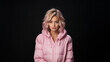 Young beautiful blonde woman wearing a pink puffer jacket with a black background in a studio.