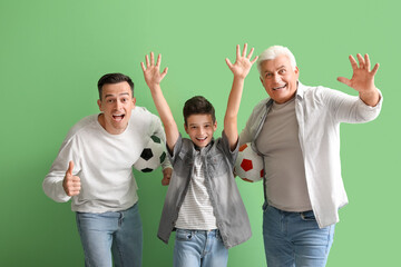 Wall Mural - Little boy with his dad and grandfather holding soccer balls on green background