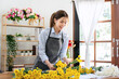 © Katcha - Female florist in apron selecting yellow chrysanthemum to creating and designing floral for arrangement