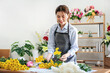 © Katcha - Female florist in apron selecting yellow chrysanthemum to creating and designing floral for arrangement