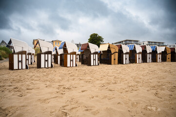 Roofed wicker beach chairs at the baltic sea beach, coast at the island of Usedom in Germany, storm and rain over the brackish water, high waves, storm warning