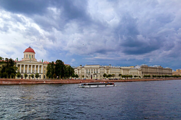 Summer landscape with Neva river and embankment of Vasilievsky island in St. Petersburg city, Russia. Beautiful panoramic view with water surface against a cloudy sky.