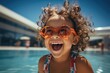 A happy little girl in sunglasses near the pool in the summer. space for text. children's summer holidays