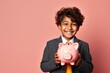 © Tymofii - Happy Ethnic Boy Holding Pink Piggy Bank