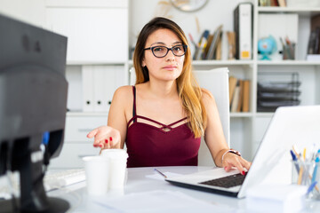 Young colombian woman in glasses working with laptop at the office table