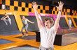 Active guy teenager trains jumping on trampoline in trampoline center