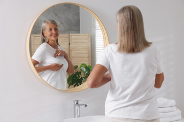 Wall Mural - Beautiful senior woman doing breast self-examination near mirror in bathroom