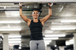 © Dusan Petkovic - A happy muscular sportswoman is doing pullups in a gym.