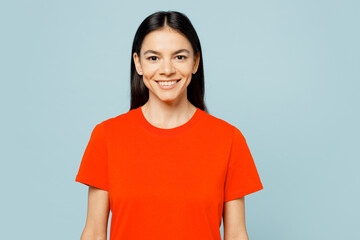 Wall Mural - Young smiling happy cheerful satisfied cool latin woman wears orange red t-shirt casual clothes looking camera isolated on plain pastel light blue cyan background studio portrait. Lifestyle concept.